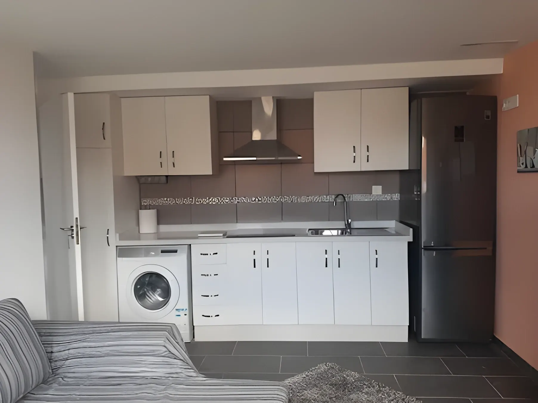 Cocina equipada con lavadora, nevera y campana extractora