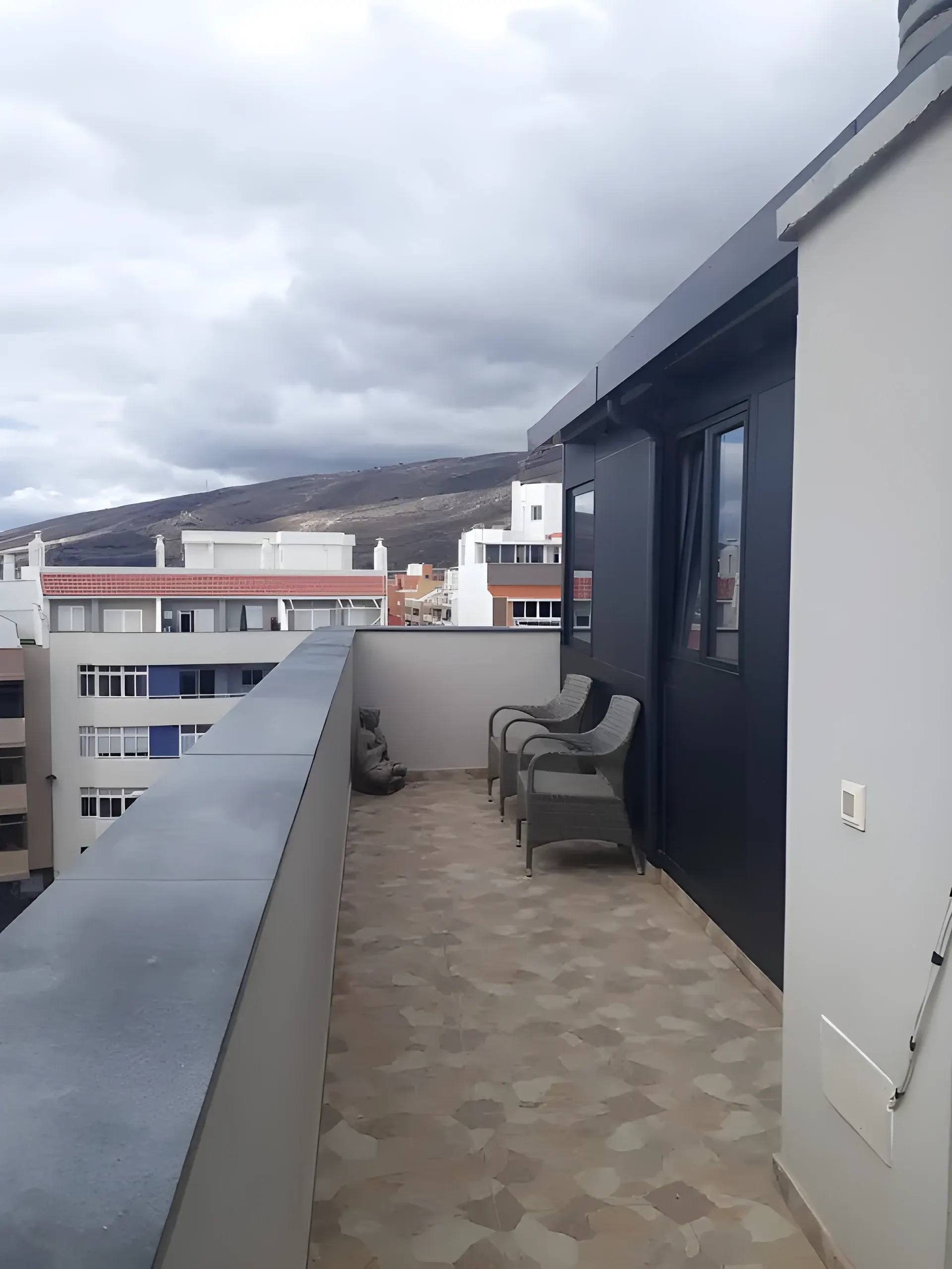 Terraza privada del ático, con suelo de baldosa y vistas a la montaña